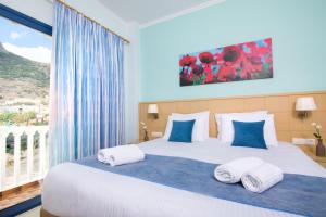 a bedroom with a large bed with blue and white pillows at Hotel Sunshine in Kamari