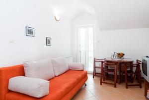 a living room with an orange couch and a table at Apartmani Villa Radovic in Risan