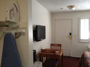 Habitación con cama y TV en la pared. en Scottish Inns en Long Beach