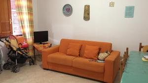 sala de estar con sofá naranja y TV en HOLIDAY HOME CON VERANDA SUL MARE e A 3 MINUTI A PIEDI DALLA SPIAGGIA, en Custonaci
