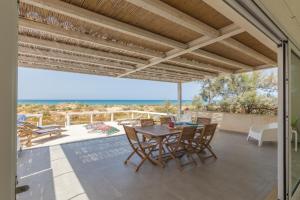 a patio with a table and chairs and the ocean at Villa Unica Terrazzo Sul Mare in Donnalucata