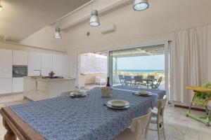 a kitchen and dining room with a blue table and chairs at Villa Unica Terrazzo Sul Mare in Donnalucata