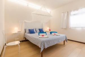 a white bedroom with a bed with blue pillows at Villa Unica Terrazzo Sul Mare in Donnalucata