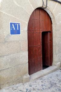 uma porta numa parede de pedra com um sinal nela em Apartment Gloria em Cáceres