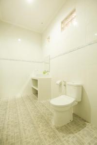 a white bathroom with a toilet and a sink at Wingsu Guest House in Canggu