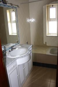 y baño con lavabo, espejo y bañera. en Apartamento das Oliveiras, en Vilamoura