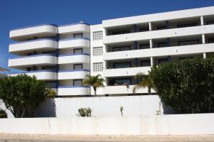 un edificio blanco con palmeras delante en Apartamento das Oliveiras, en Vilamoura