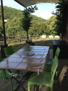 uma mesa de madeira com cadeiras verdes num quintal em villa chez marie Meuble tourisme 3 etoiles em Sari Solenzara