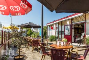 eine Terrasse mit Tischen, Stühlen und einem Sonnenschirm in der Unterkunft Stacaravan Jade in IJmuiden