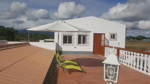 una casa blanca con una sombrilla en la cubierta en VIP House-Praia Francesca, en São Tomé