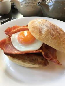 un sándwich de desayuno con un huevo y tocino en un plato en The Hideaway At Windermere (Adults only), en Windermere