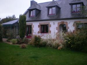 a white house with red windows and a yard at Chambres d'hotes de Pouldiguy in Lannion