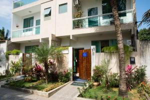 a white building with a door and a palm tree at Pousada da Gigoia - Barra da Tijuca in Rio de Janeiro