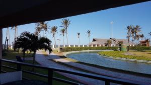 uma piscina de água com palmeiras e uma cerca em Aquaville Térreo - Porto das Dunas - CEARÁ - AV80101 em Aquiraz