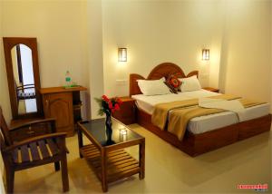a bedroom with a bed and a chair and a table at Holiday Villa in Thekkady