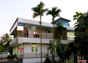 un bâtiment blanc avec des palmiers devant lui dans l'établissement Holiday Villa, à Thekkady