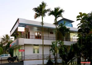a white building with palm trees in front of it at Holiday Villa in Thekkady
