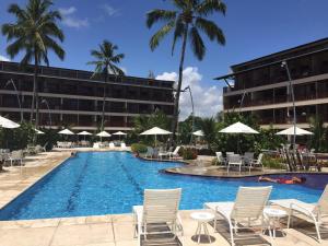 ein Swimmingpool mit Stühlen und Sonnenschirmen neben einem Gebäude in der Unterkunft Nannai Residence - Muro Alto in Porto De Galinhas