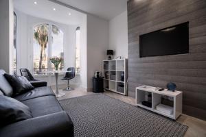 a living room with a couch and a television on a wall at Carré d'OR! Park view! in Nice