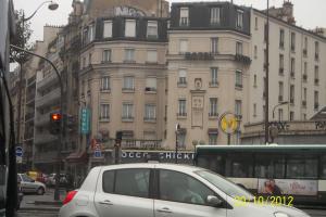 Une voiture en argent qui descend dans une rue de la ville avec un bus dans l'établissement Hôtel de la Terrasse, à Paris