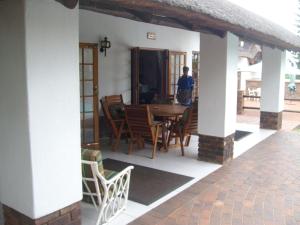a porch with a table and chairs and a person at Oaktree Lodge Guest House in Kyalami
