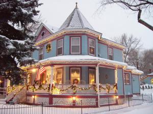 コロラドスプリングスにあるHolden House 1902 Bed & Breakfast Innの雪の中のクリスマス灯付青い家