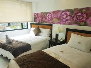 a bedroom with two beds and a flower painting on the wall at Hotel Santa Monica in Fusagasuga