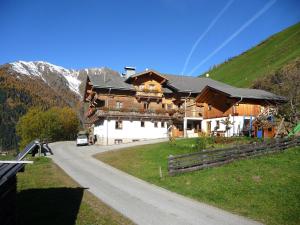 a large wooden house on a road in the mountains at Apartmenthaus Gutwenger in Innervillgraten