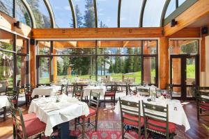 ein Restaurant mit Tischen, Stühlen und Fenstern in der Unterkunft Moraine Lake Lodge in Lake Louise