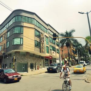 a man riding a bike in front of a building at Hotel Santa Monica in Fusagasuga
