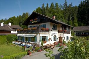 een groot wit huis met tafels en stoelen ervoor bij Gasthaus am Zierwald in Grainau