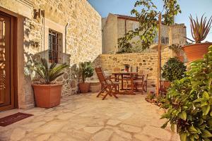 een patio met een tafel, stoelen en planten bij Villa Kapela in Sívas