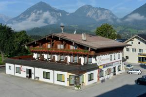 ein Gebäude mit Blumen auf dem Dach mit Bergen im Hintergrund in der Unterkunft Post Appartements in Strass im Zillertal