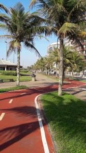 a red road with palm trees on the side at Mar Azul in Solemar