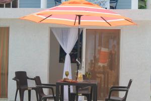 a table with an orange umbrella and two chairs at Sunny Beach Apartments in San Andrés