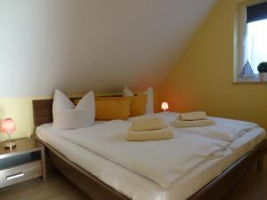 ein Schlafzimmer mit einem Bett mit weißen Laken und Kissen in der Unterkunft Family Apartments Tom in Ostseebad Karlshagen