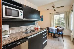 a kitchen with a sink and a microwave at Altué Apart Hotel in Mar de las Pampas