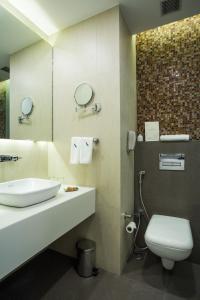 a bathroom with a sink and a toilet and a mirror at The Fern Residency Mumbai in Mumbai