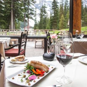 a table with a plate of food and a glass of wine at Moraine Lake Lodge in Lake Louise +20 photos
