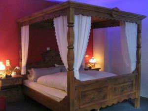 a bedroom with a canopy bed with white sheets at Gasthaus Laubacher Wald in Laubach