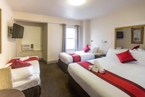 a hotel room with three beds and a tv at City Square Motel in Melbourne