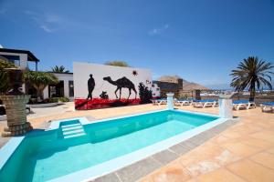 a swimming pool in a yard with a painting of a camel at Casa de Hilario in Yaiza