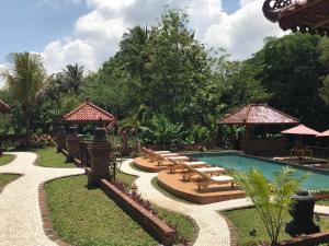 a pool at a resort with chairs and umbrellas at Rumah Dharma 2 Riverside in Borobudur