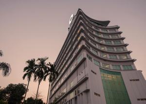 un grand bâtiment avec des palmiers devant lui dans l'établissement Wyne Hotel, à Yangon