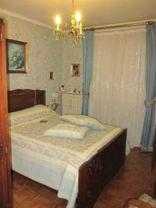 a bedroom with a bed with blue curtains and a chandelier at BORD' ADOUR in Soues