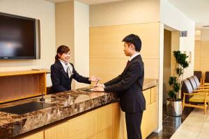 a man and a woman standing at a counter at Hotel Lumiere Nishikasai in Tokyo