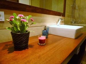 a bathroom counter with a sink and a candle and flowers at Apartamentos Nazareno in Seville