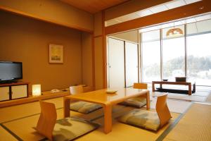 Okuizumo-cho的住宿－玉峰山莊日式旅館，客厅配有桌椅和电视。
