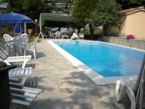 einen Pool mit Stühlen, einem Tisch und einem Sonnenschirm in der Unterkunft Albergotto Natalina in Grazzano Badoglio