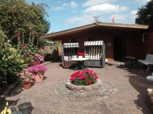 um pátio com duas cadeiras, uma mesa e flores em Ferienwohnung Stanke em Büdelsdorf